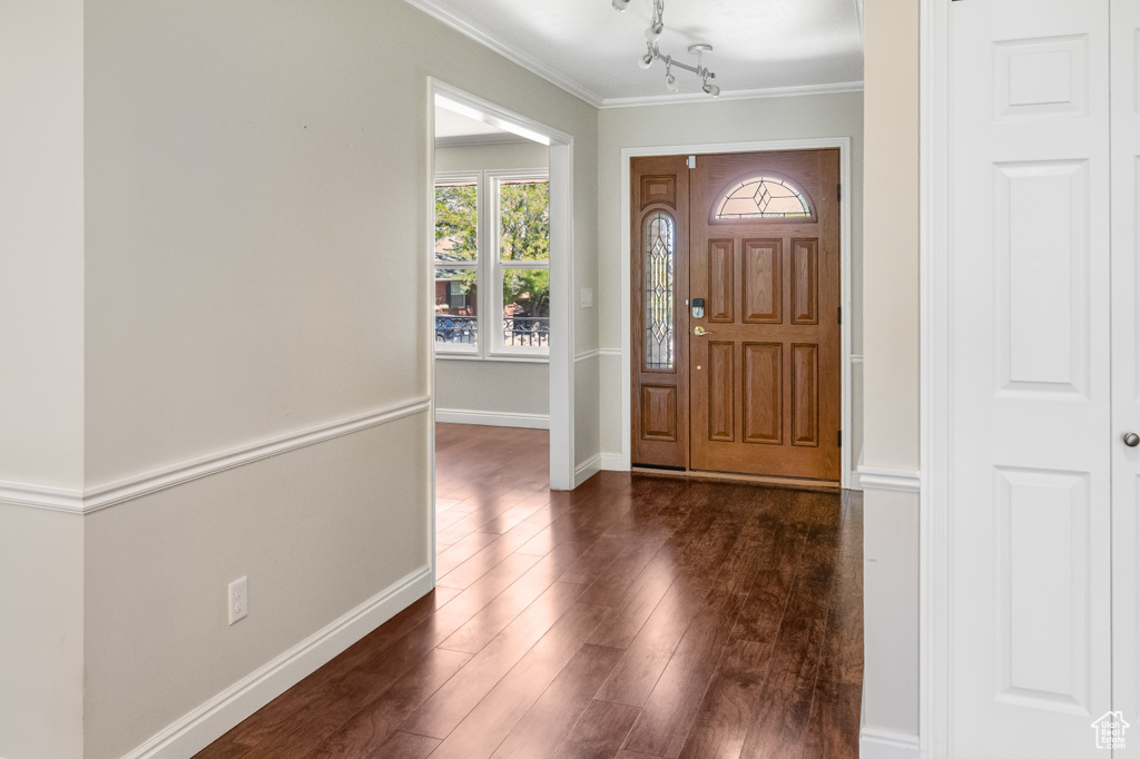 Foyer with ornamental molding and dark wood finished floors