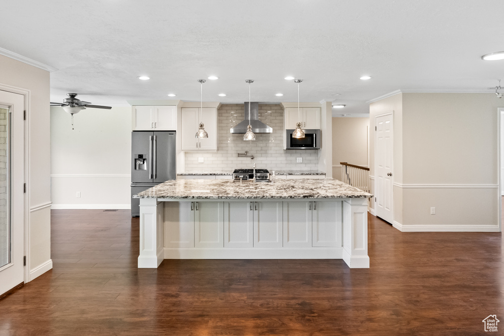 Kitchen featuring a spacious island, backsplash, appliances with stainless steel finishes, wall chimney range hood, and ceiling fan