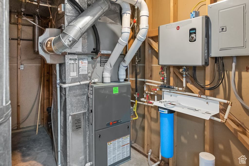 Utility room featuring water heater, heating unit, and electric panel