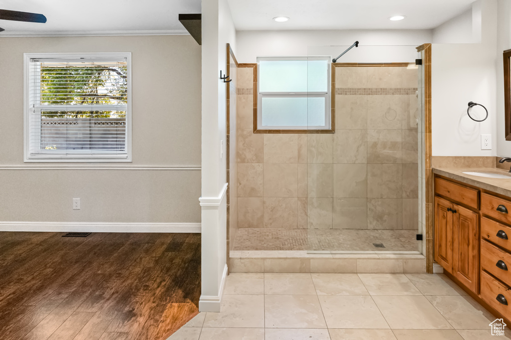 Bathroom with vanity, tiled shower, ornamental molding, ceiling fan, and recessed lighting