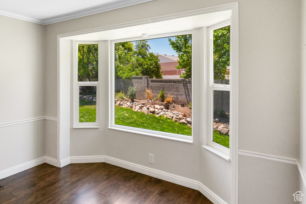 Empty room featuring dark wood-style floors and ornamental molding