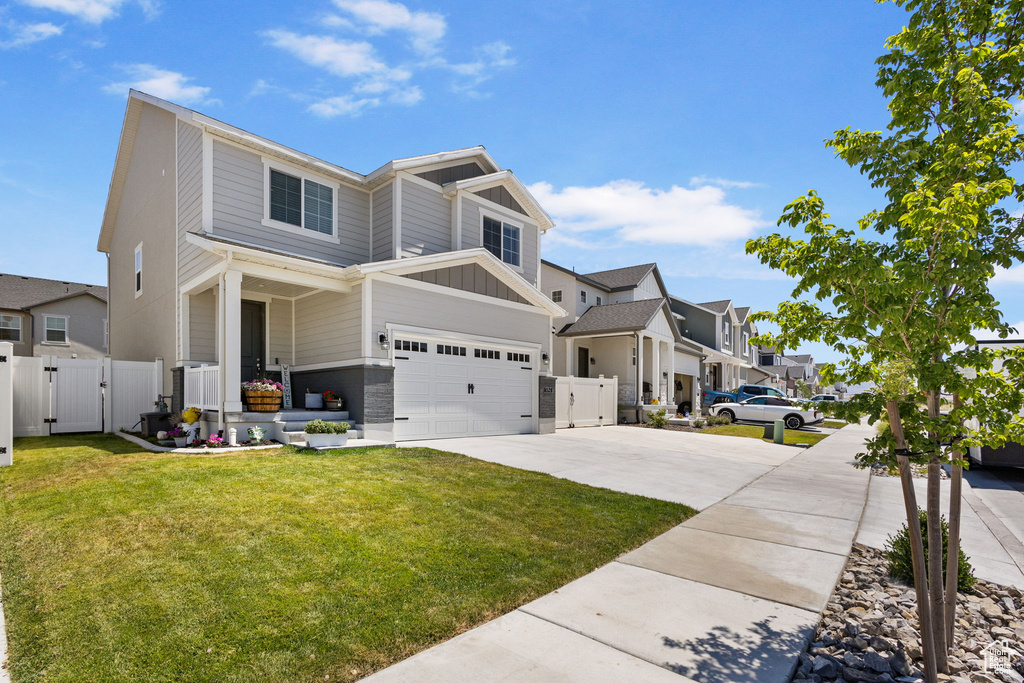 View of front of home with a gate, board and batten siding, driveway, a garage, and a residential view