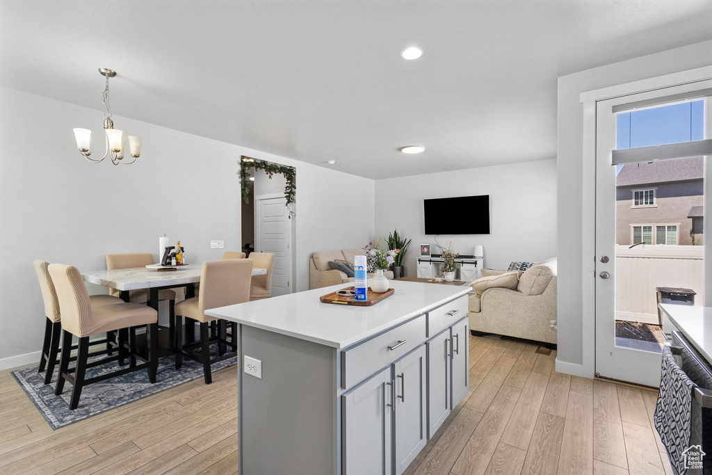 Kitchen featuring light wood finished floors, a chandelier, open floor plan, gray cabinetry, and recessed lighting