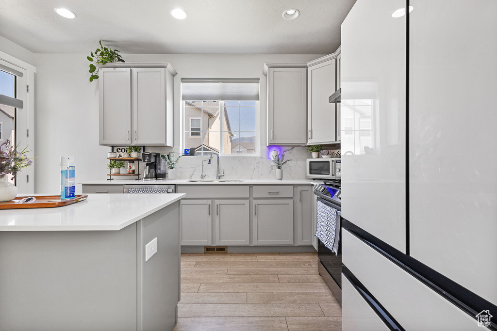 Kitchen featuring recessed lighting, appliances with stainless steel finishes, light wood-style flooring, light countertops, and decorative backsplash