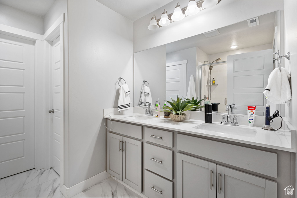 Bathroom featuring marble look tiles, double vanity, and a shower stall