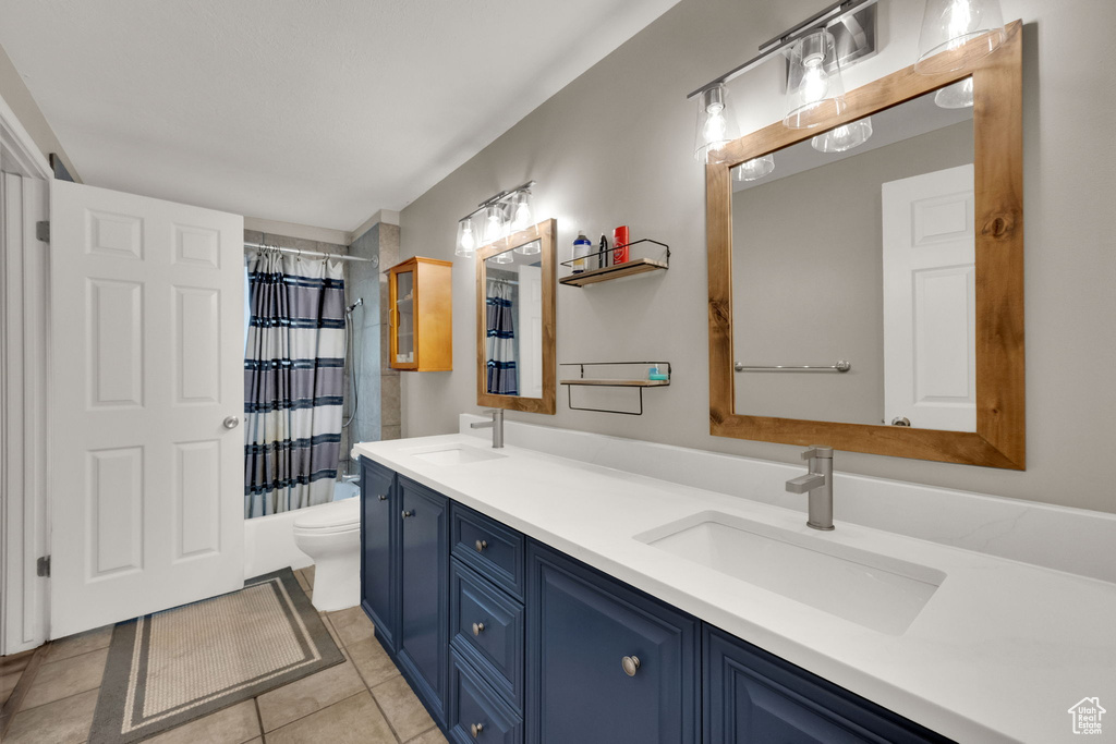 Full bathroom featuring double vanity, tile patterned flooring, and shower / bath combination with curtain