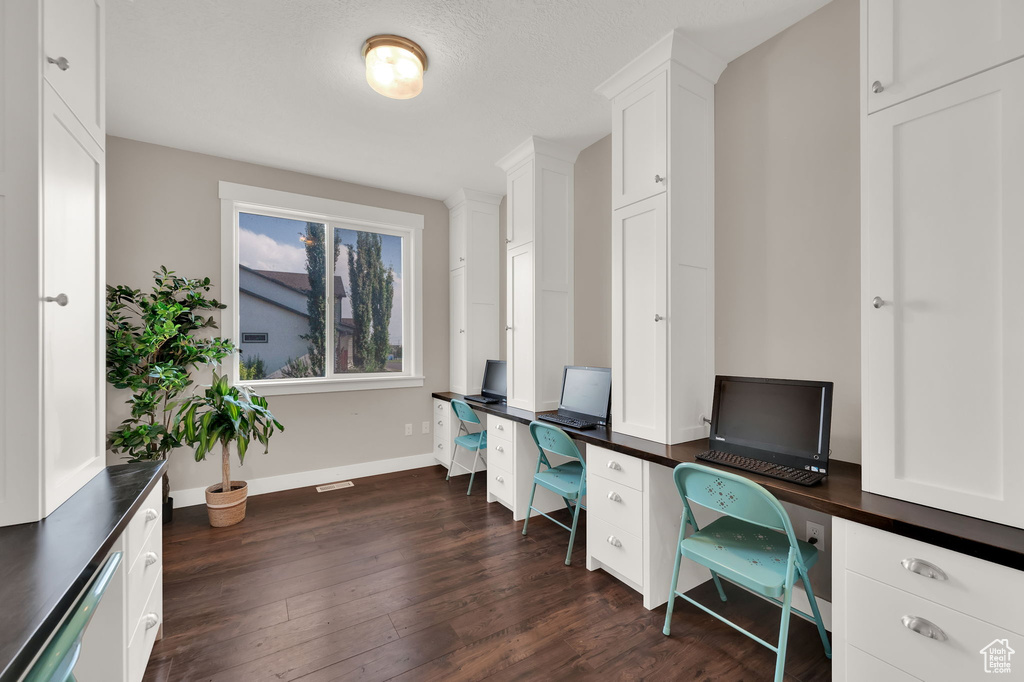 Home office featuring dark wood-type flooring and baseboards