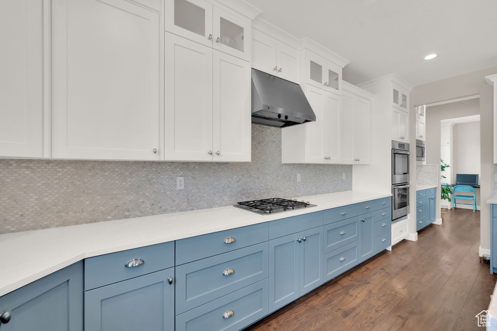 Kitchen featuring blue cabinets, under cabinet range hood, dark wood-style floors, light countertops, and recessed lighting