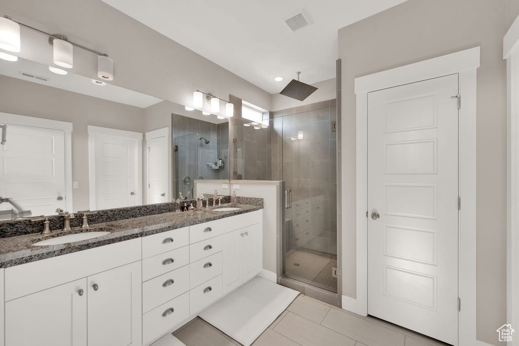 Full bathroom featuring a stall shower, double vanity, and tile patterned flooring