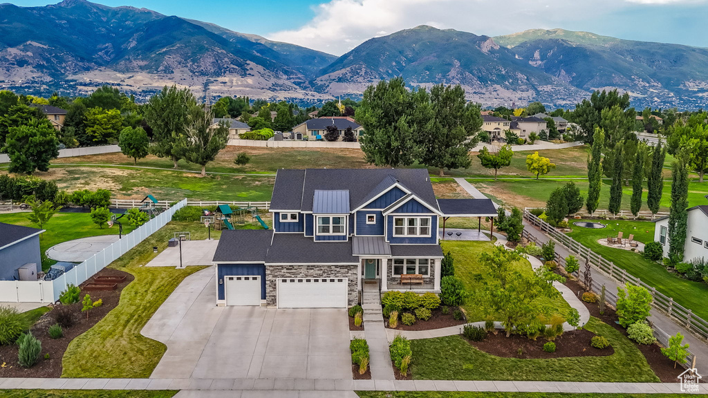 View of front of house featuring concrete driveway, stone siding, a fenced backyard, an attached garage, and a porch