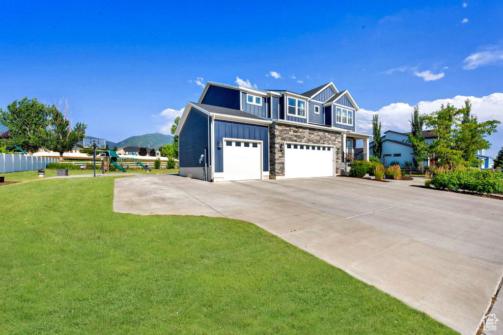 View of front of house with board and batten siding, an attached garage, stone siding, driveway, and a mountain view