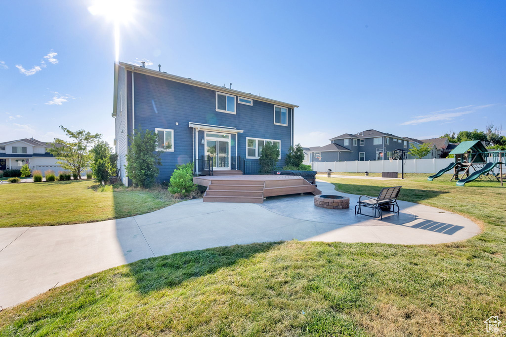 Rear view of property featuring a fire pit, a patio, a playground, a wooden deck, and a residential view