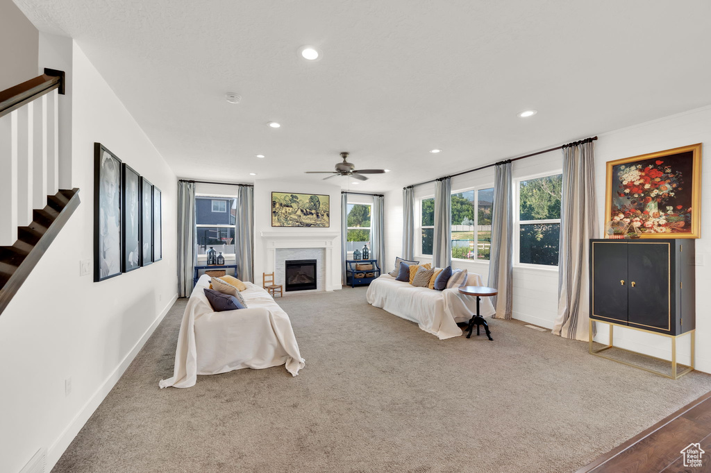Living room featuring recessed lighting, stairs, ceiling fan, a glass covered fireplace, and carpet