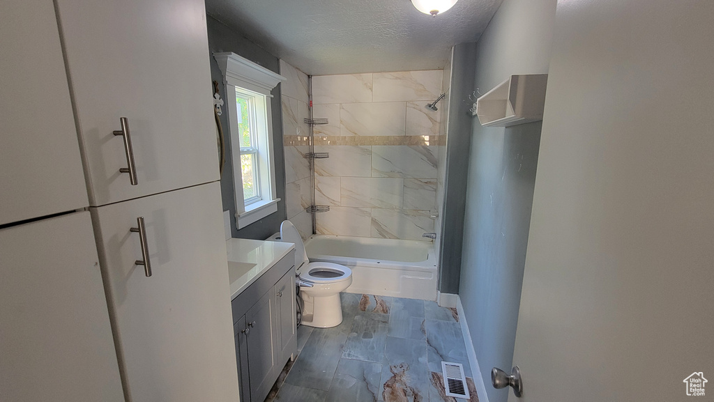 Full bath with vanity, washtub / shower combination, a textured ceiling, and marble finish floors
