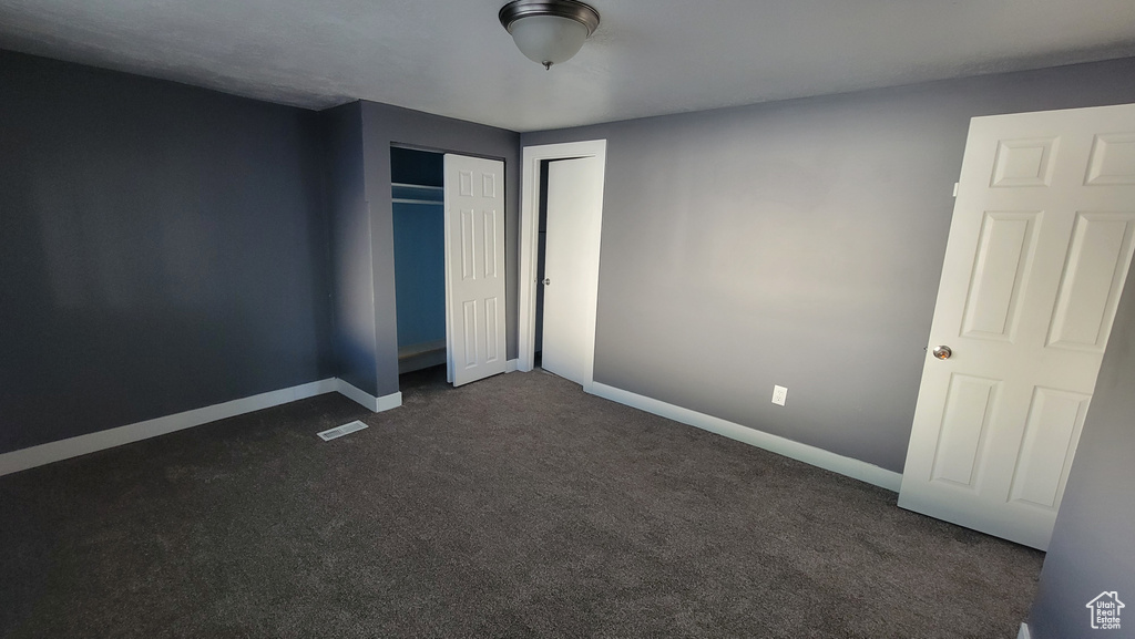 Unfurnished bedroom featuring dark carpet and baseboards