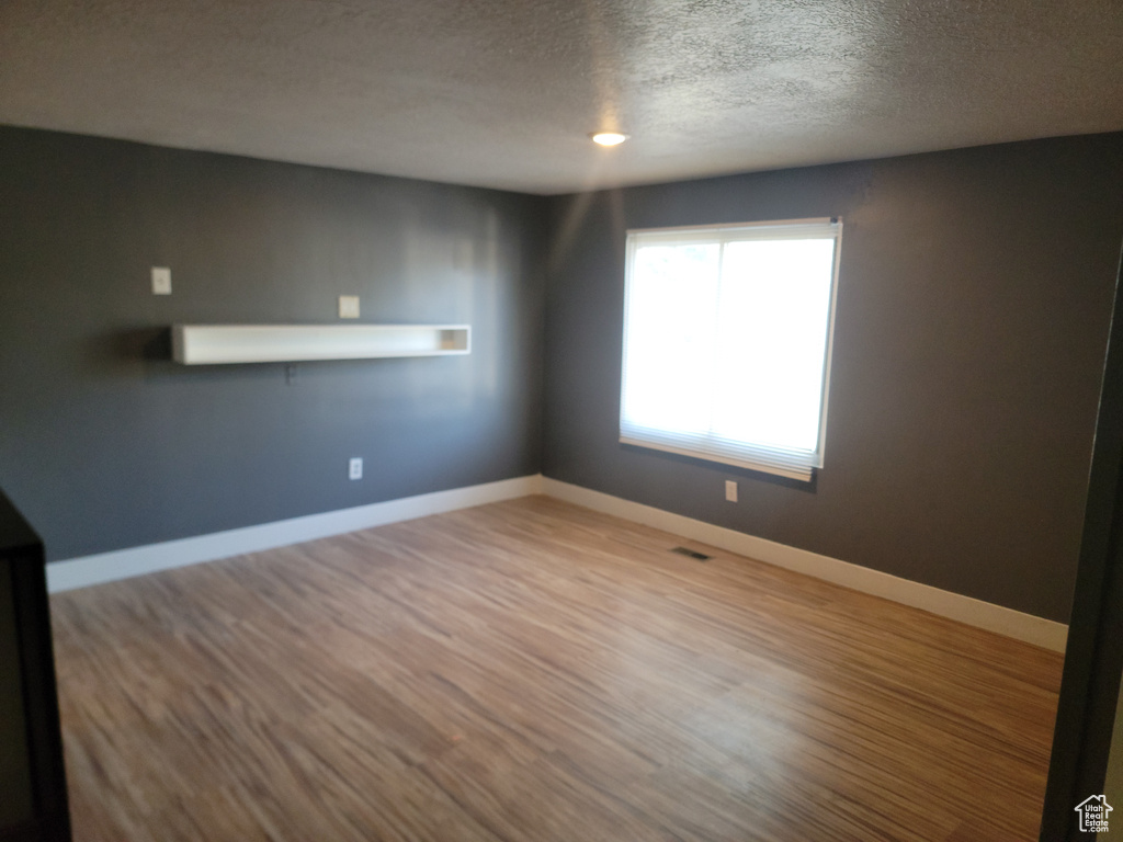 Spare room with wood finished floors and a textured ceiling