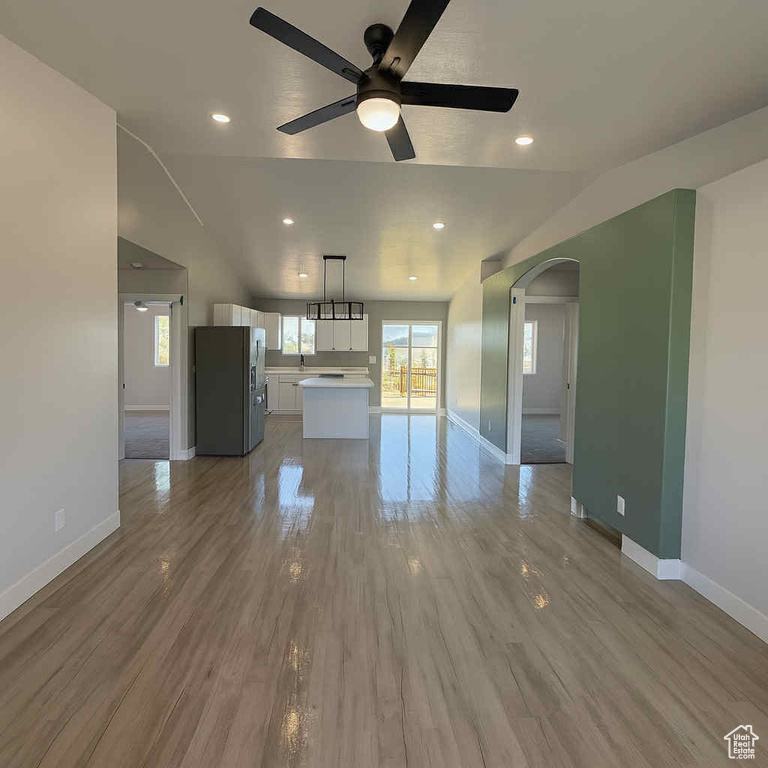 Unfurnished living room with arched walkways, a ceiling fan, recessed lighting, and wood finished floors