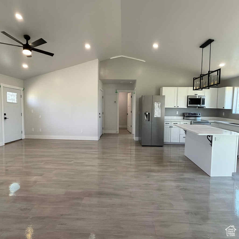 Kitchen featuring stainless steel appliances, ceiling fan, lofted ceiling, white cabinets, and open floor plan