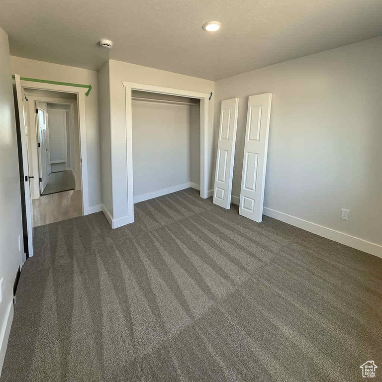Unfurnished bedroom with dark carpet, a closet, and recessed lighting