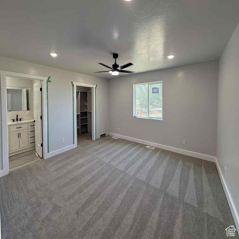 Unfurnished bedroom featuring carpet, a walk in closet, ensuite bathroom, recessed lighting, and ceiling fan