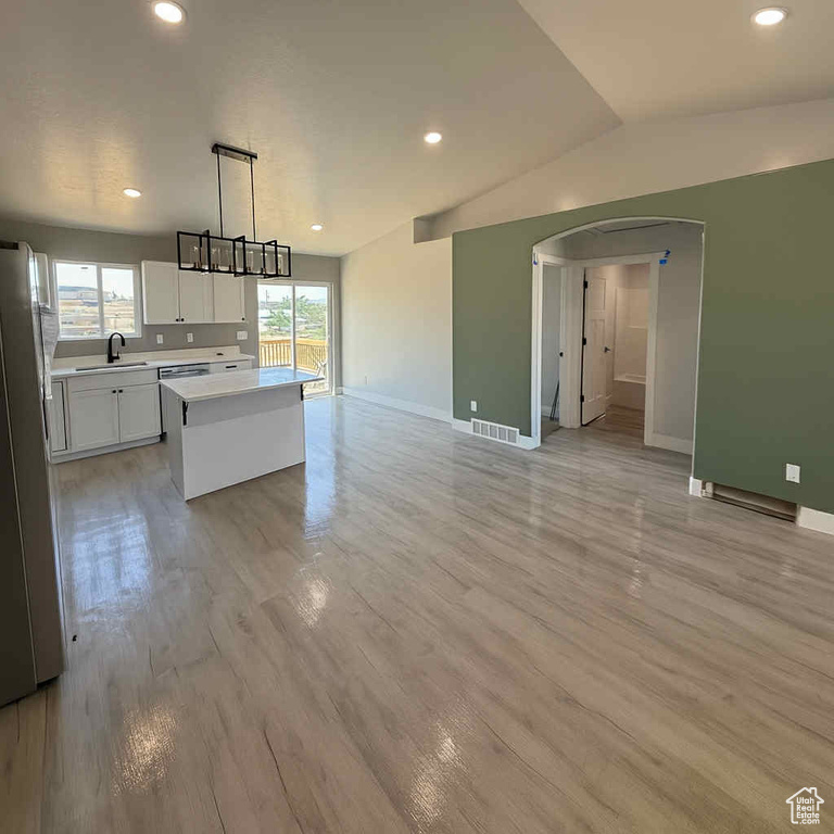 Kitchen featuring light countertops, a center island, white cabinetry, freestanding refrigerator, and recessed lighting