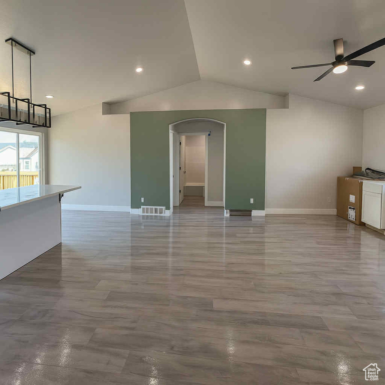 Unfurnished living room featuring ceiling fan, arched walkways, lofted ceiling, recessed lighting, and wood finished floors