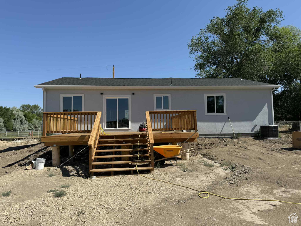Back of house with a deck, stairs, roof with shingles, and stucco siding