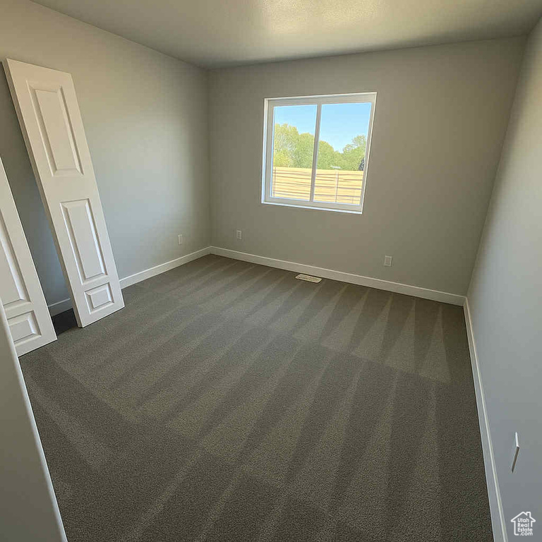 Empty room featuring dark colored carpet