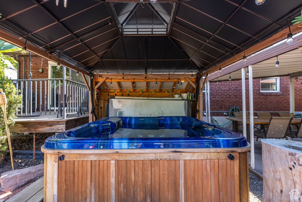 Wooden terrace featuring a hot tub and a gazebo