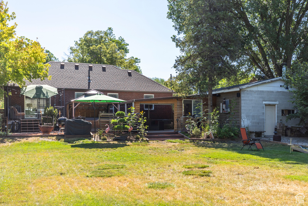 Rear view of property featuring a yard, a deck, and a gazebo