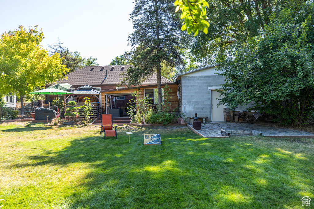 Back of property with a gazebo, a lawn, and concrete block siding