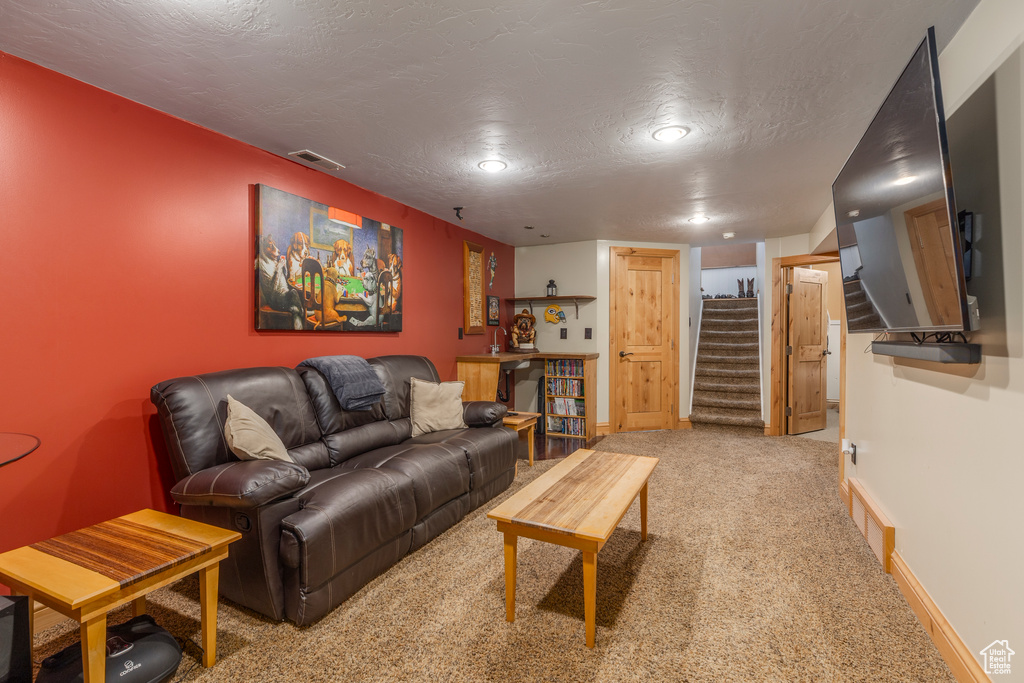 Living area with carpet flooring, stairway, a textured ceiling, and recessed lighting