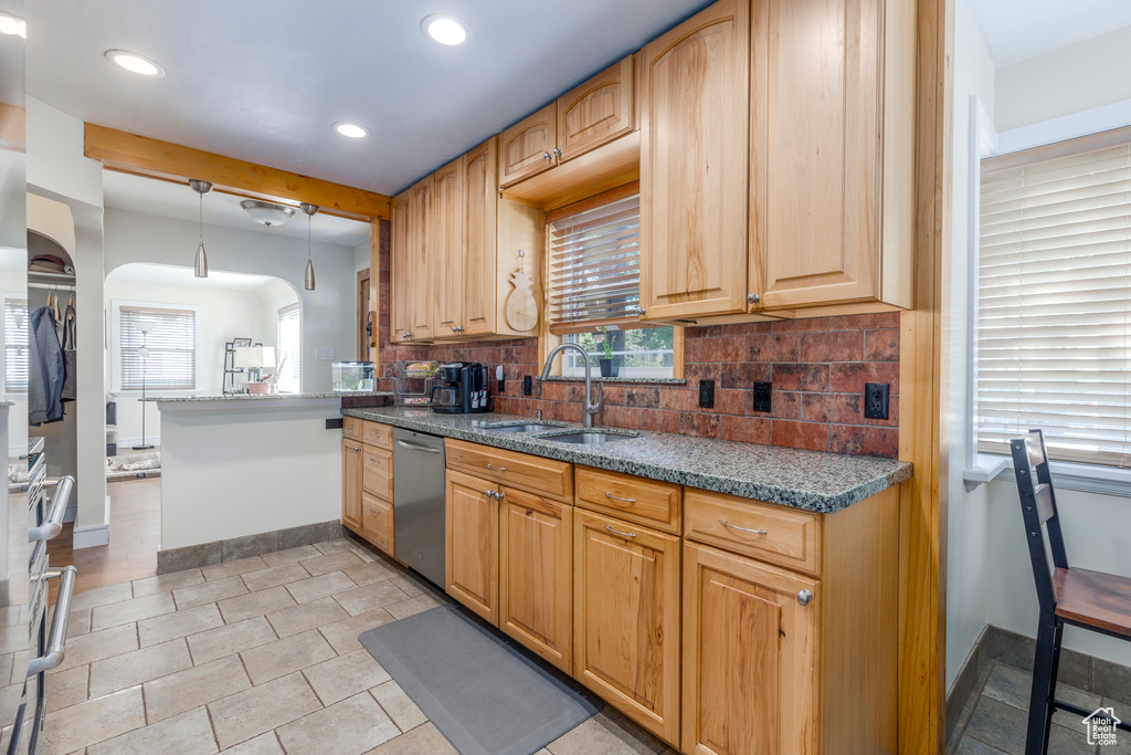 Kitchen with arched walkways, tasteful backsplash, recessed lighting, hanging light fixtures, and stainless steel dishwasher