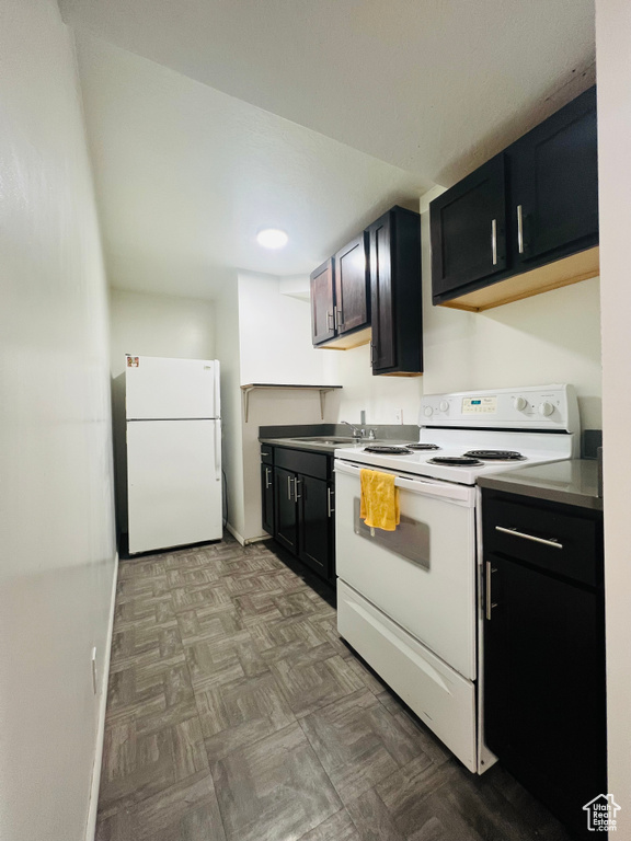 Kitchen with white appliances, dark cabinets, and recessed lighting
