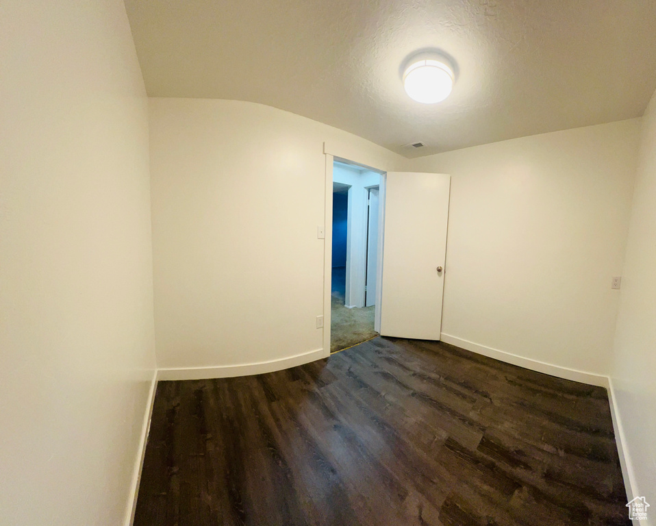 Unfurnished room featuring dark wood-type flooring and baseboards