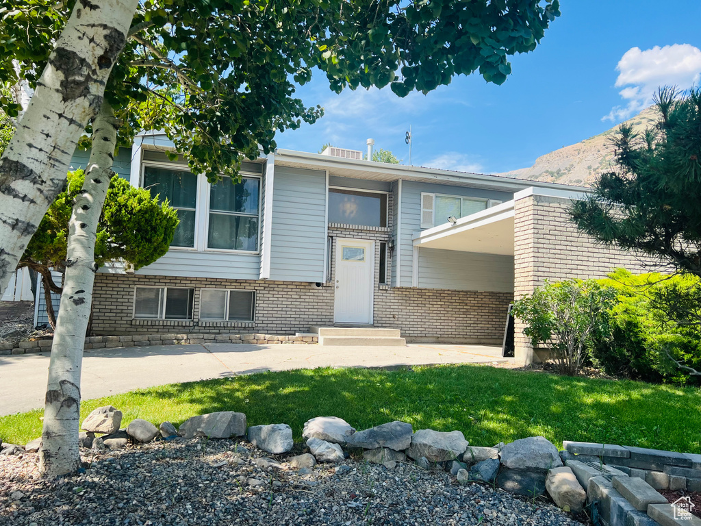 View of front of house with brick siding, a front lawn, and a mountain view