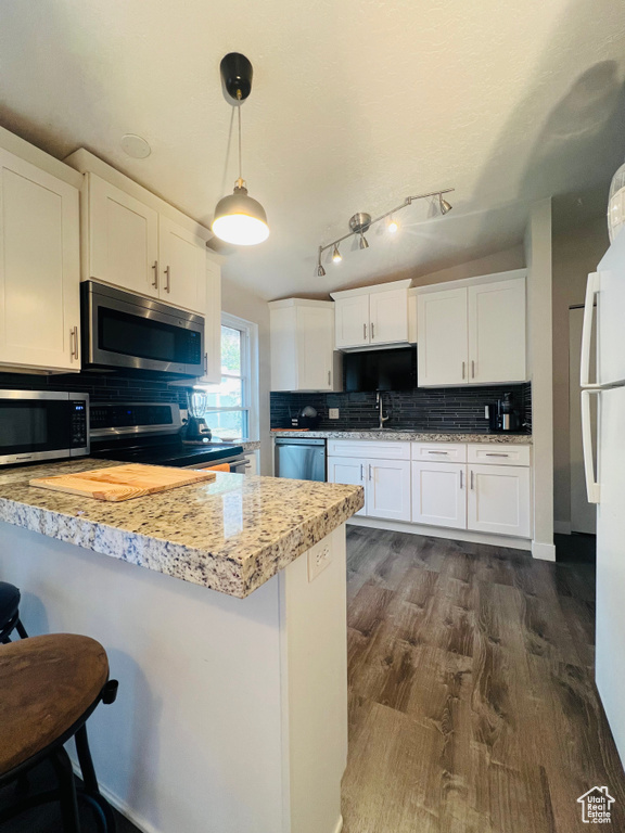 Kitchen featuring appliances with stainless steel finishes, white cabinets, light countertops, and decorative backsplash