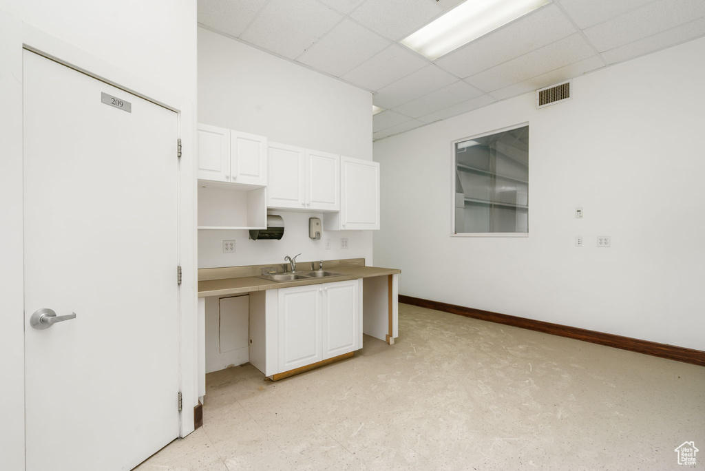 Kitchen featuring a paneled ceiling and white cabinets