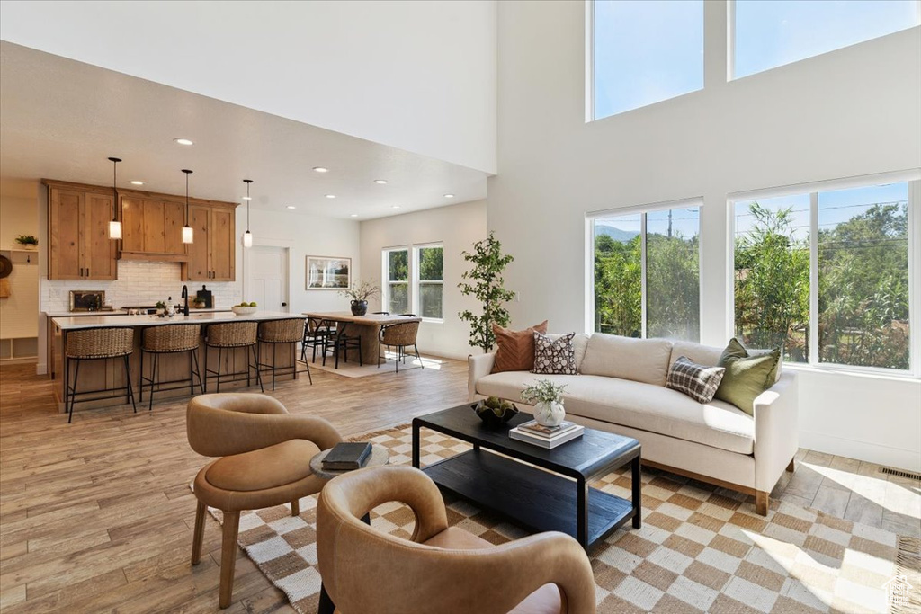 Living room with light wood-style flooring, recessed lighting, and a towering ceiling
