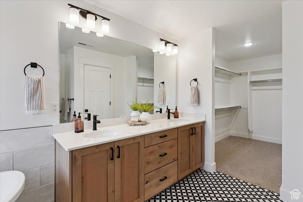 Full bath featuring double vanity, a walk in closet, and tile patterned floors