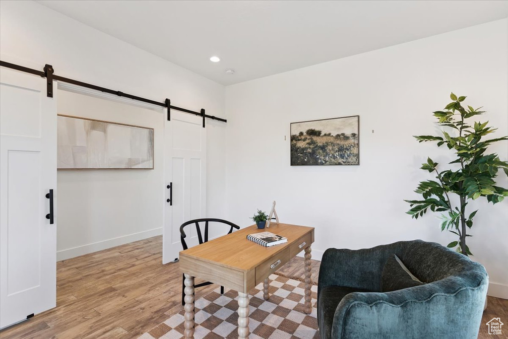 Home office with a barn door, wood finished floors, and recessed lighting