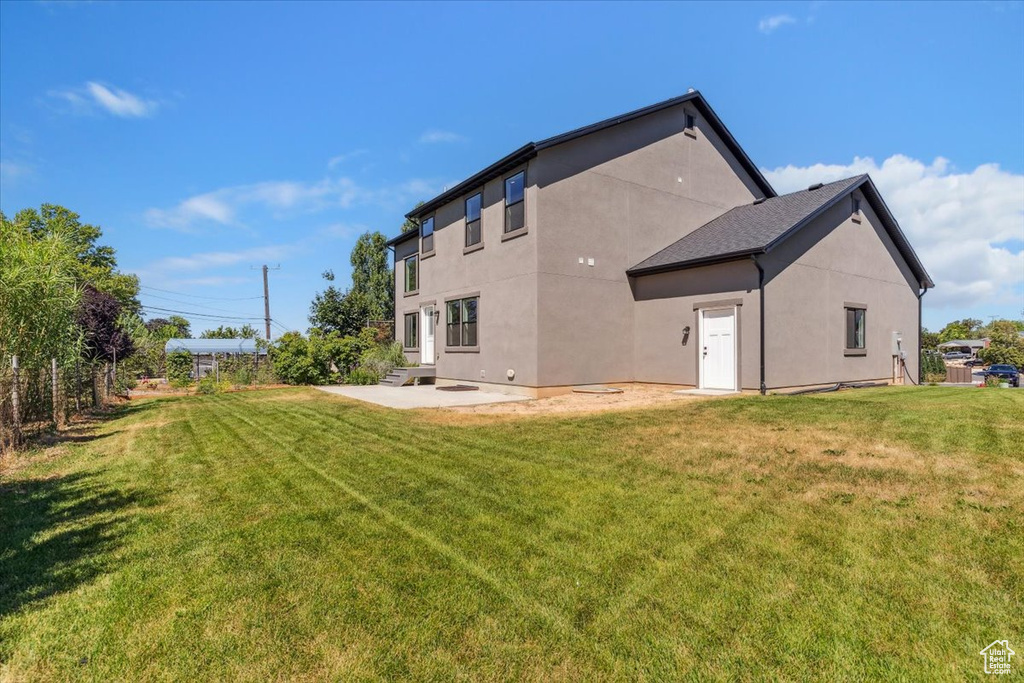 Rear view of property featuring stucco siding, a yard, and a patio area
