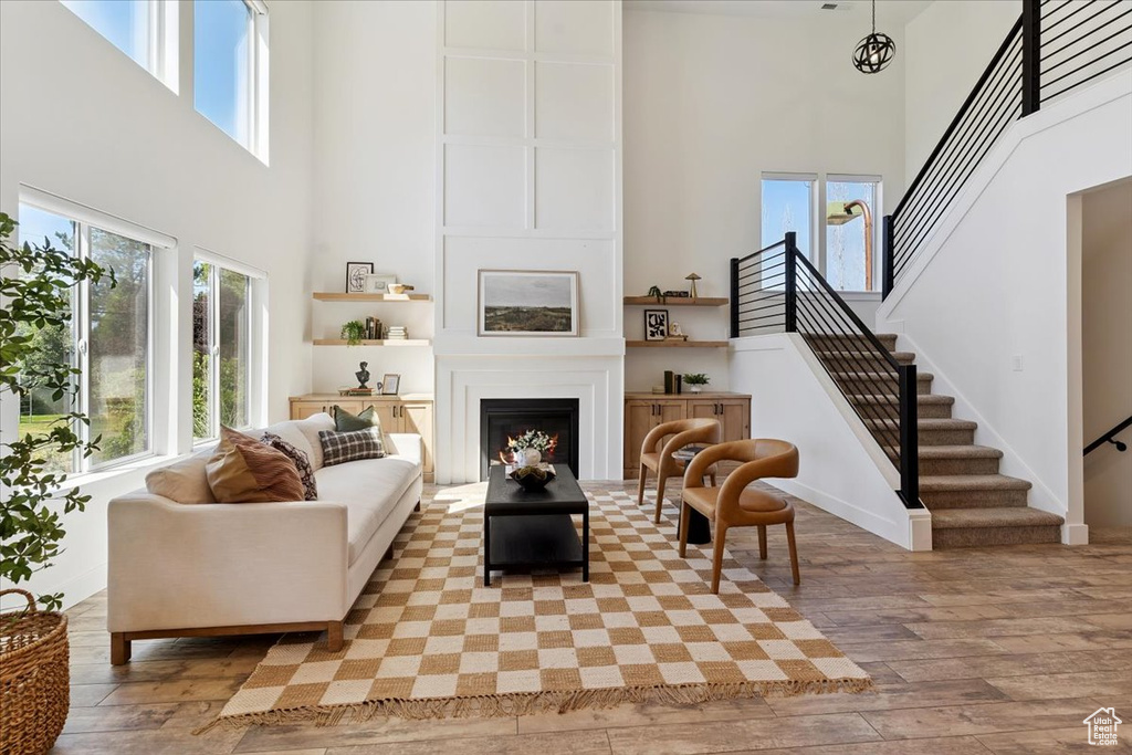 Living area featuring a high ceiling, hardwood / wood-style floors, stairway, and a large fireplace