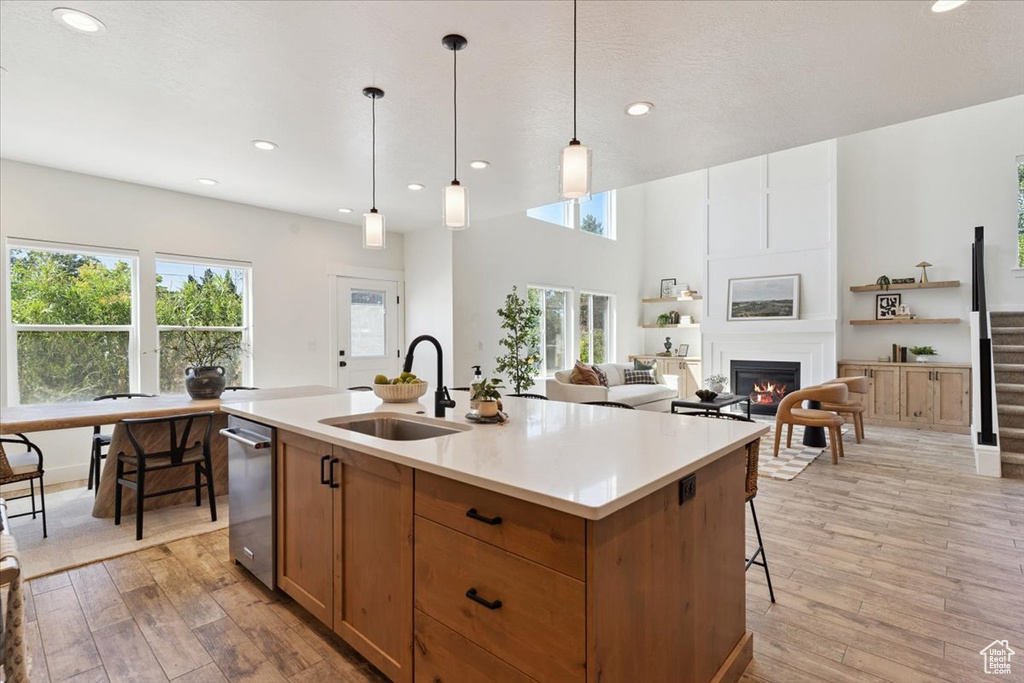 Kitchen featuring light wood finished floors, healthy amount of natural light, a fireplace, light countertops, and recessed lighting