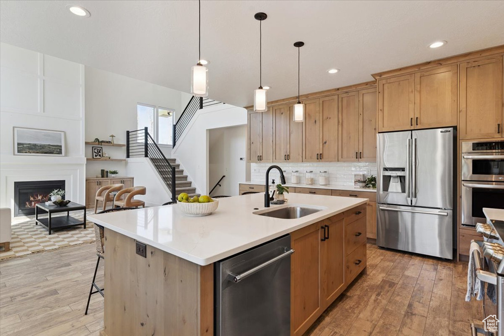 Kitchen featuring stainless steel appliances, light wood finished floors, light countertops, recessed lighting, and tasteful backsplash