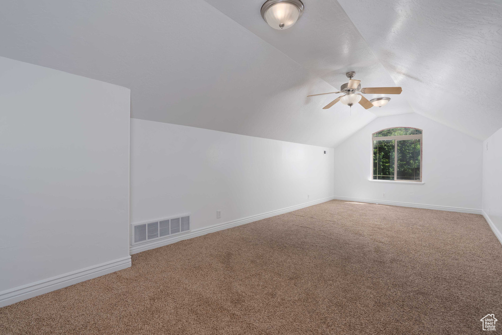 Bonus room with lofted ceiling, a ceiling fan, and carpet flooring