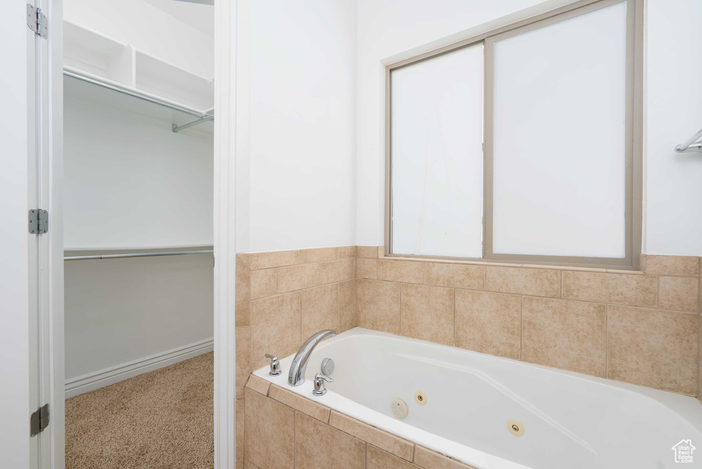 Full bathroom with a jetted tub and a spacious closet