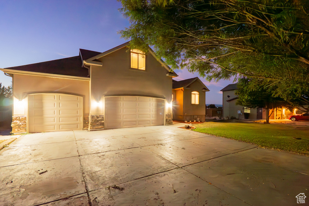 Traditional-style house featuring driveway, a front yard, stucco siding, stone siding, and a garage