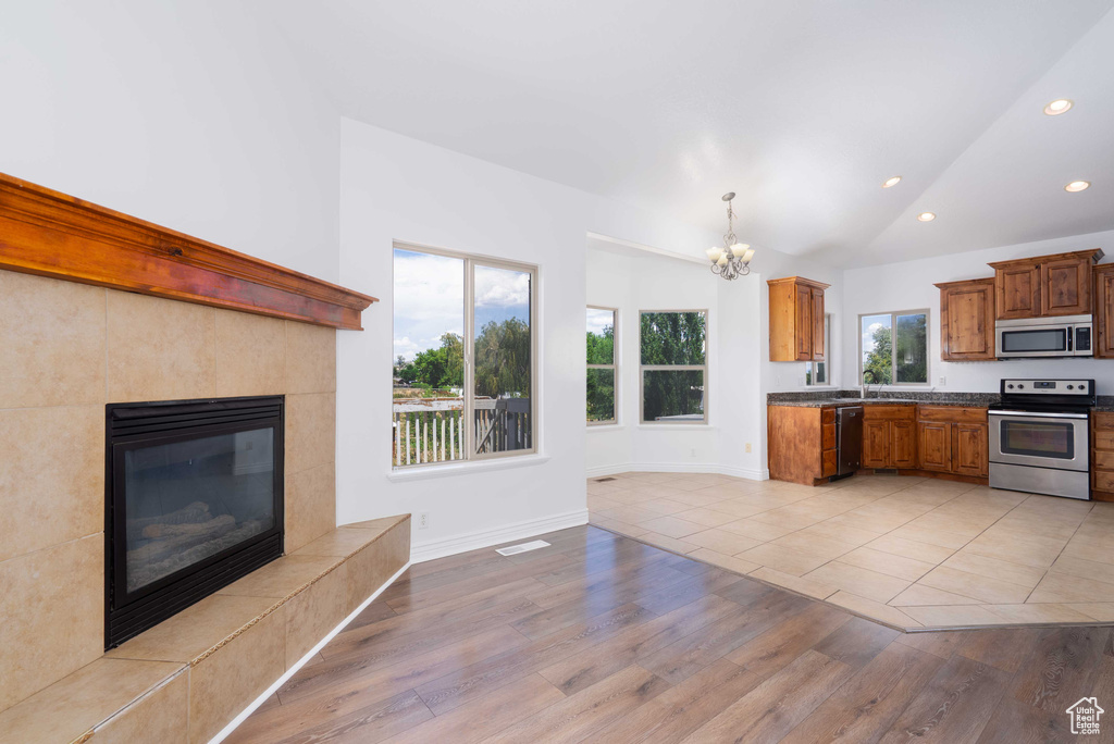 Kitchen with light wood-style flooring, appliances with stainless steel finishes, a chandelier, recessed lighting, and dark countertops