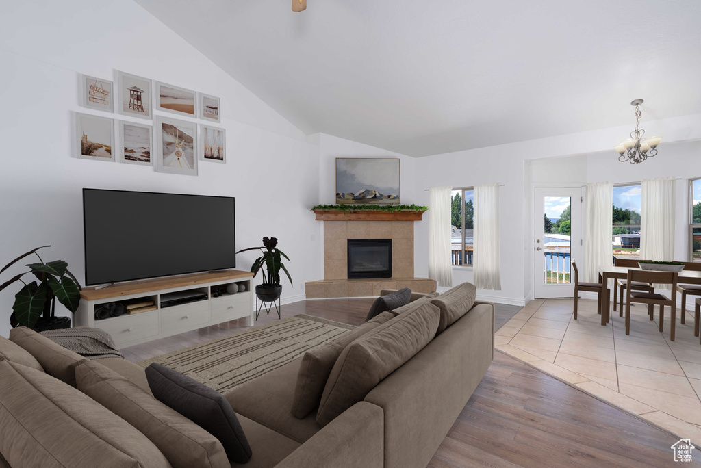 Living area featuring a chandelier, vaulted ceiling, light wood finished floors, and a fireplace